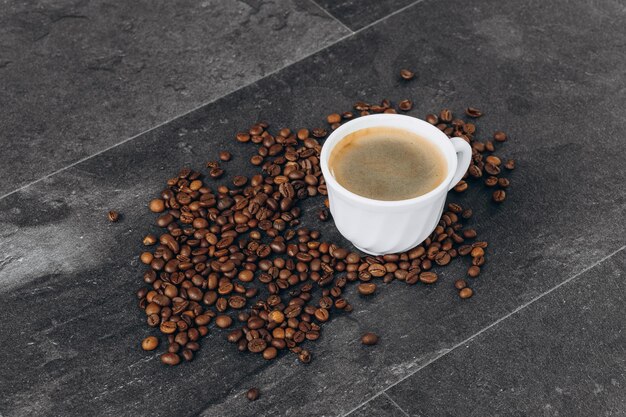 Cup of black coffee with beans on wooden table