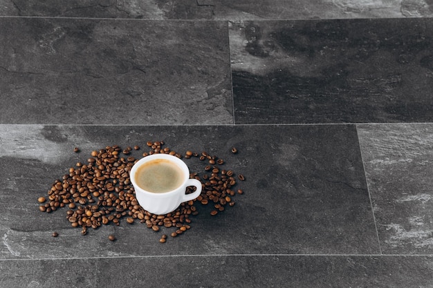 Cup of black coffee with beans on wooden table