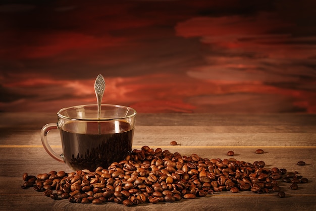 Cup of black coffee with coffee beans on the table