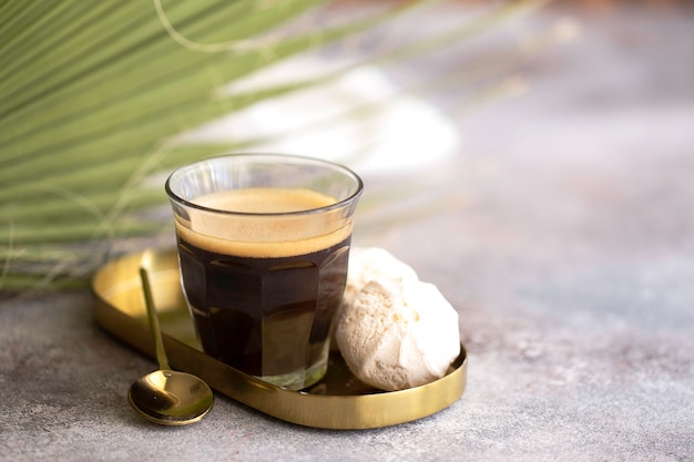 Cup on black coffee with green palm leaves