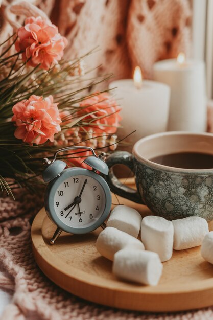 Tazza di caffè nero su un vassoio di legno con dessert e bouquet a colori e con candele