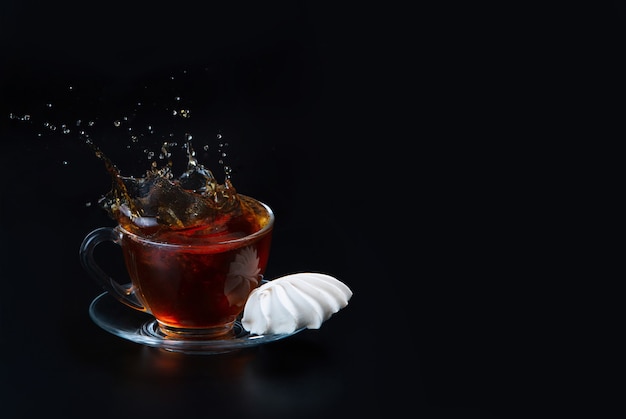 A cup of black tea on a black isolated surface