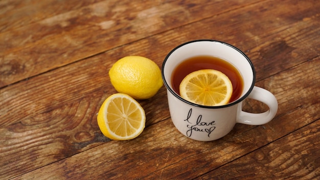 Cup of black tea and lemons on wooden table top view Hot tea for the treatment and prevention of colds Breakfast drink