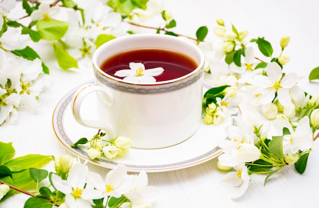 A cup of black tea in white apple blossoms