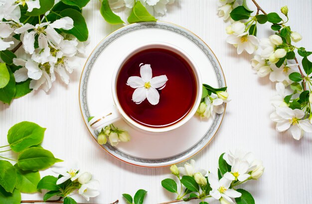 A cup of black tea in white apple blossoms.