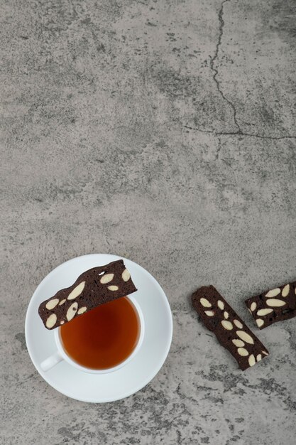 Cup of black tea with cocoa crackers on stone table.