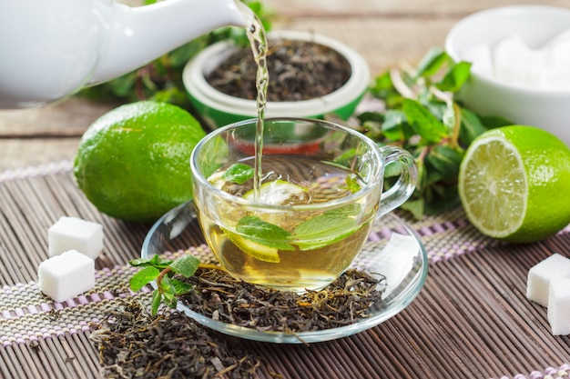 Cup of black tea with mint leaves on a wooden table