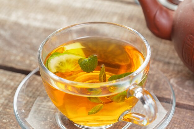 Tazza di tè nero con foglie di menta su un tavolo di legno