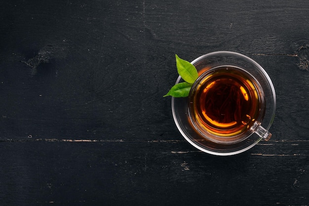 Photo a cup of black tea on a wooden background top view copy space