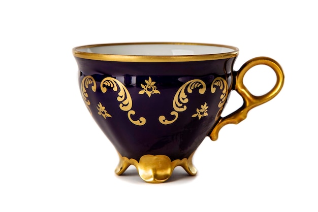 A cup of blue color with a golden pattern isolated on a white background closeup