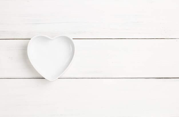 Cup or bowl empty heart-shaped on white wood plank texture for background.