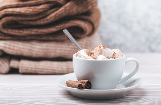 Cup of cacao and pile of knitwear