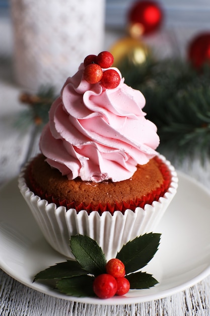 Cup-cake met room op schotel met Kerstdecoratie op houten lijstachtergrond