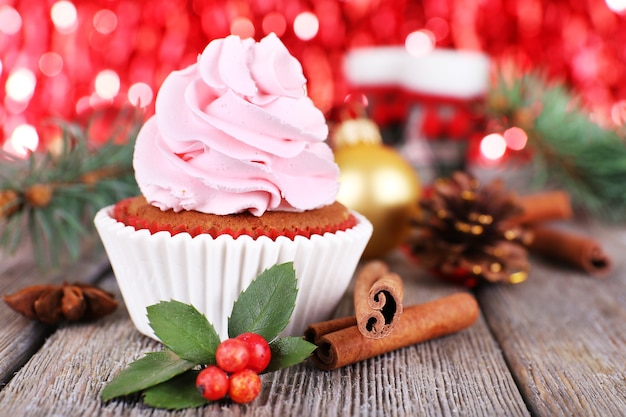 Cup-cake with cream and Christmas decoration on wooden table and shine brightly background