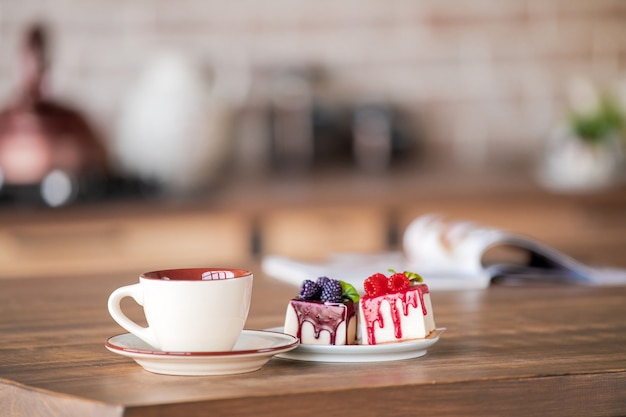 A cup and cakes on a plate stand on the tablein the kitchen