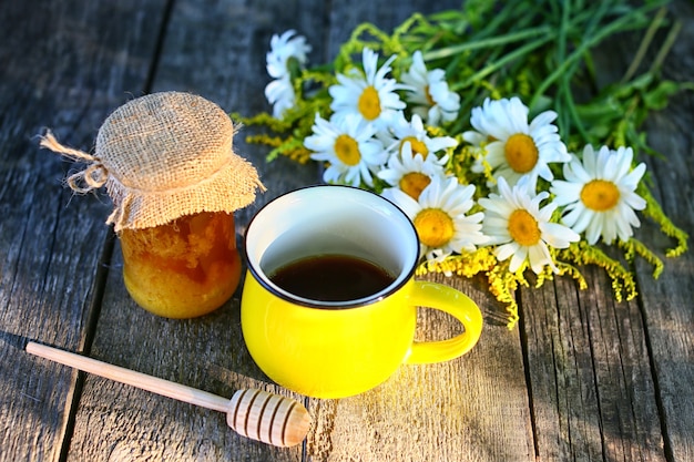 Cup of camomile tea and honey on wooden table