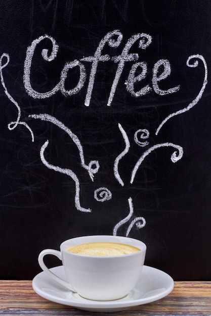 cup of cappuccino and black chalkboard with handwritten inscription coffee