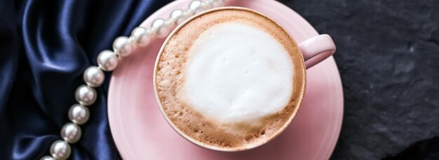 豪華なビンテージ ホリデー ブランドのパリのカフェでサテンと真珠のジュエリー背景有機コーヒーとラクトース フリー ミルクと朝食のカプチーノのカップ