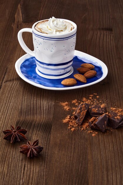 A cup of cappuccino chopped chocolate spices and almonds