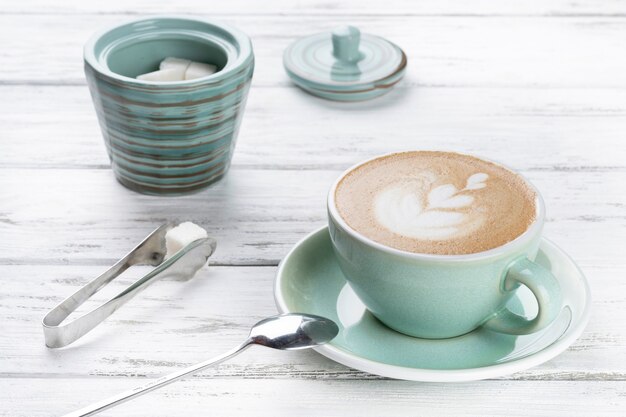 Tazza di caffè cappuccino in una tazza blu su fondo di legno bianco