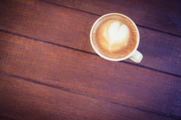 Cup of cappuccino with coffee art on wooden table