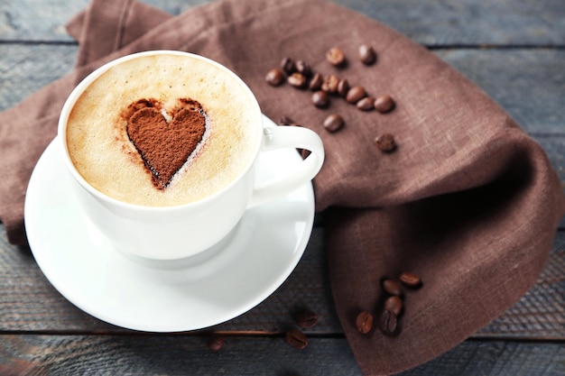 Cup of cappuccino with heart of cocoa on wooden table