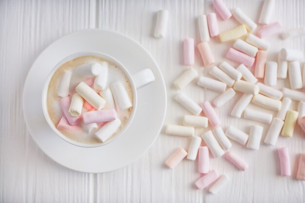 A cup of cappuccino with marshmallows on a white background