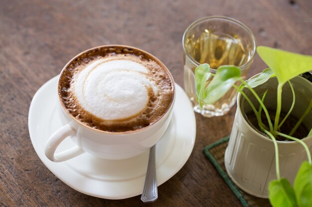 木製の背景にカプチーノのカップ