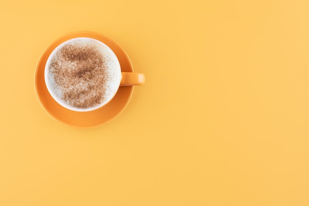 Cup of cappuchino coffee on a yellow background Space for text