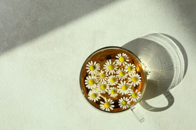 Cup of chamomile tea on white textured table