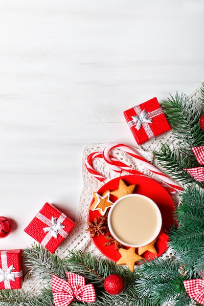 Cup of cocoa, gifts and fir-tree branches on a white wooden table.