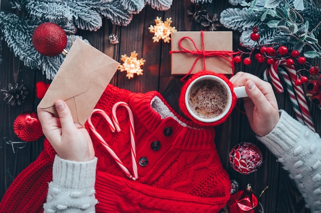 A cup of cocoa and a letter in the hands on the background of the Christmas decor