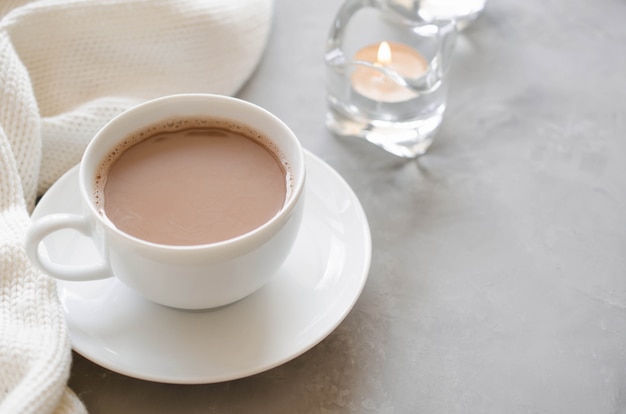 Cup of cocoa on a table, candles and knited blanket.