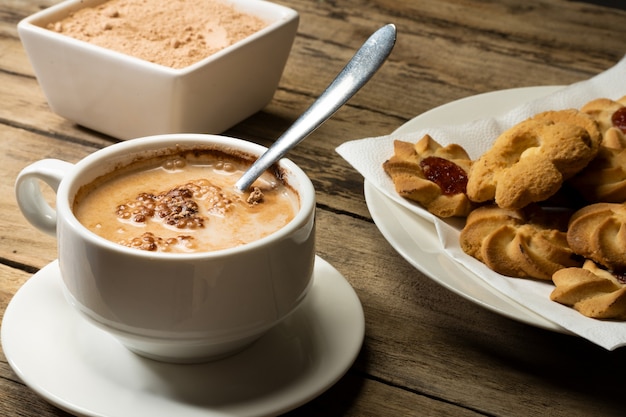 Cup of cocoa with lumps with pastes and cocoa powder on rustic table