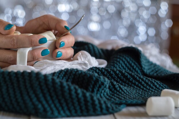 A cup of cocoa with marshmallow in female hands with a blue manicure on a shiny background