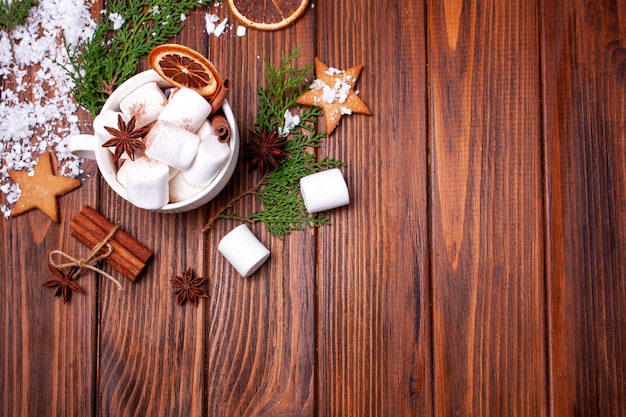 A cup of cocoa with marshmallows on a wooden table. View from above. Christmas card. Empty space