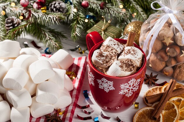 Cup of cocoa with white marshmallow and holiday snacks on Christmas table