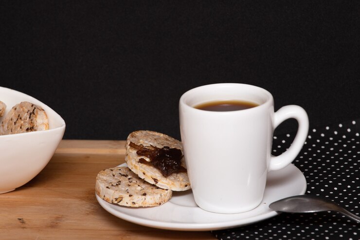 Photo a cup of coffe beside a  rice vegan cookies with jelly on the top  and a bowl full of rice cookies