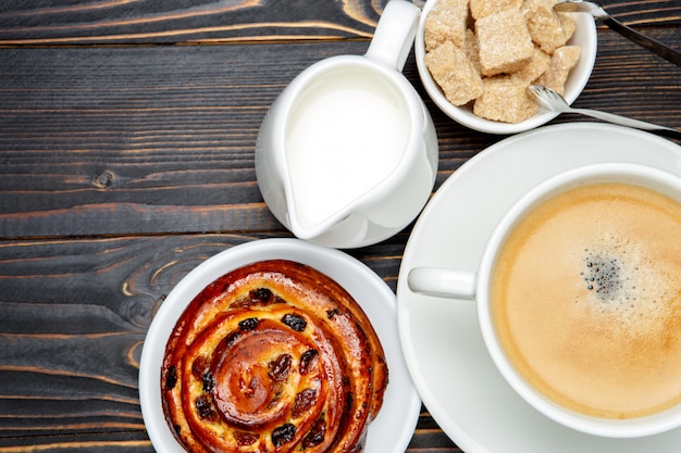 Cup of coffe and cinnabon on wooden background