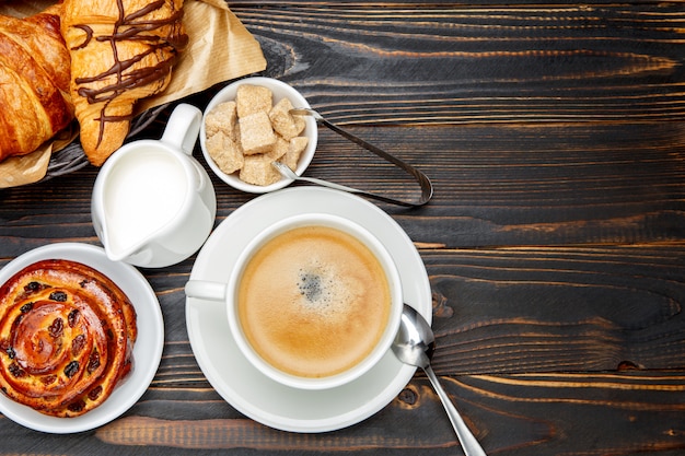 Cup of coffe and cinnabon on wooden background