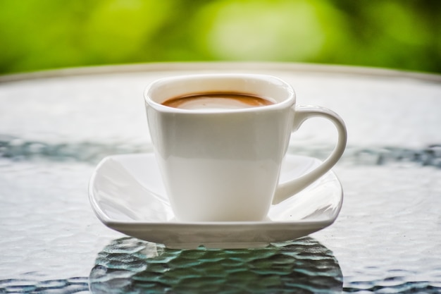 A cup of coffe put on the glass table