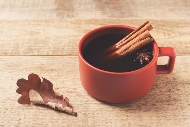 木の背景、秋の気分のコーヒースパイスと葉のカップ