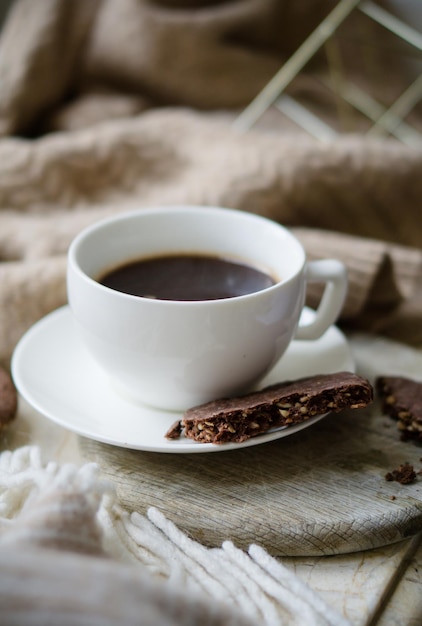 Cup of coffe with milk and chocolate cookies on warm wool blanket