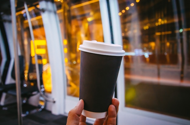 空港で一杯のコーヒーマンの手と黒いカップ