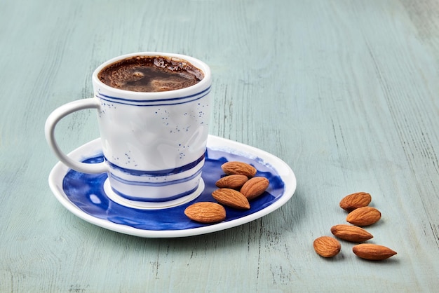 Cup of coffee and almond on a blue wooden table