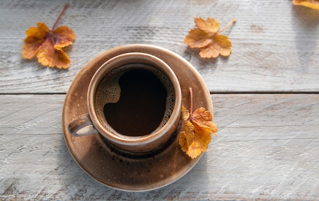 A cup of coffee and autumn leaves on the windowsill