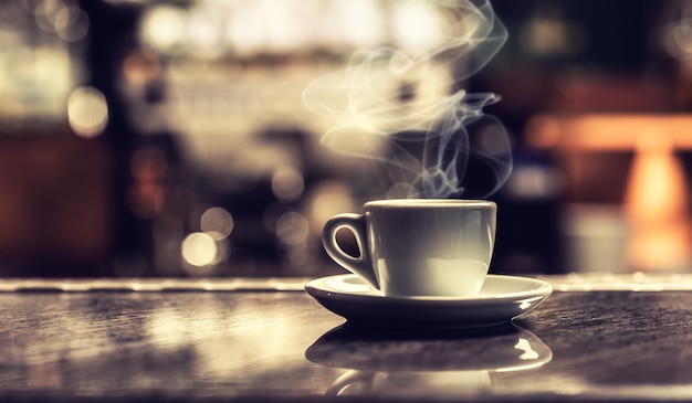 Cup of coffee on bar desk in night club.