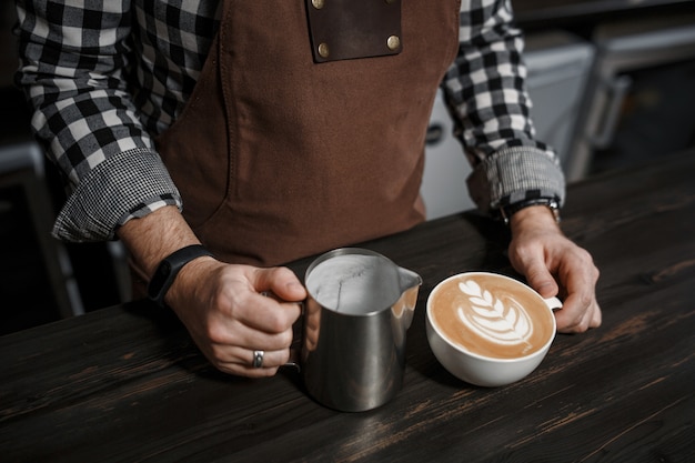 Cup of coffee and barista hands at the bar in a modern cafe