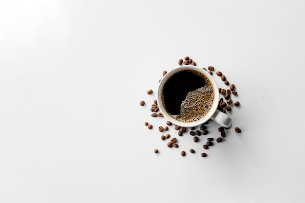 Tazza di caffè e fagioli sul fondo bianco della tavola. vista dall'alto