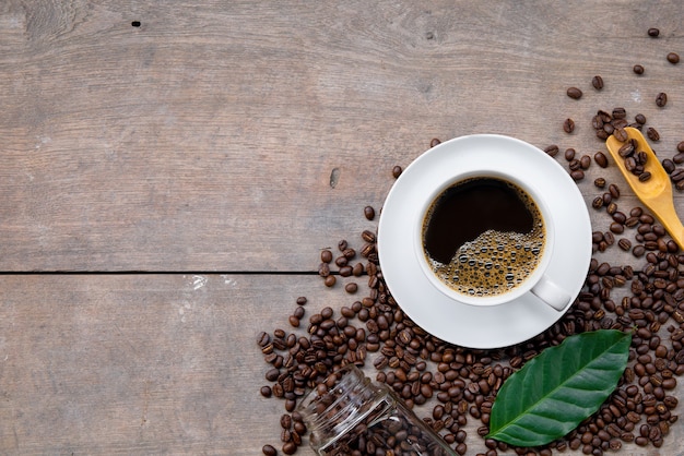 木の床の背景にコーヒーと豆のカップ。上面図